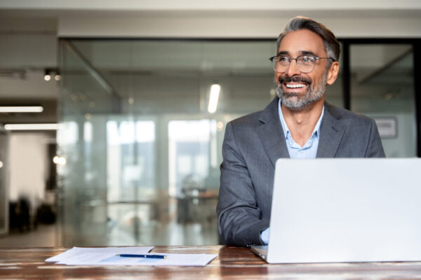 Smiling businessman working on laptop in office